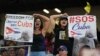 Asistentes al partido entre EEUU y Cuba levantan carteles con mensajes de protesta contra el régimen cubano. (AP/Wilfredo Lee)