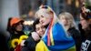 Dos mujeres envueltas en una bandera ucraniana se abrazan durante un flash mob en protesta por el abuso sexual de soldados rusos en Ucrania. (AFP/Kena Betancur).