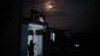Residentes del barrio Naranjal Norte intentan obtener conectividad a Internet y aire fresco en una calurosa noche de verano en el techo de una casa