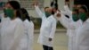 Médicos cubanos alzan sus puños en ceremonia de despedida antes de su partida a Andorra, en marzo pasado. (Yamil Lage/AFP)