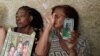 Osmara Garcia Mesa (izq.) y Amparo Rivera muestran fotos de sus hijos, desaparecidos en el mar cuando intentaban emigrar a EEUU. (Yamil Lage/AFP)