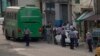 Sospechosos de coronavirus son evacuados en un bus del MINSAP y escoltados por la policía cerca del Mercado de Cuatro Caminos, en La Habana. (AP/Ismael Francisco)
