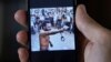 Un hombre que no quiso ser identificado muestra en su teléfono al rapero contestatario Maykel Castillo El Osorbo. (REUTERS/Alexandre Meneghini)