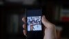 Un hombre que no quiso ser identificado muestra en su teléfono al rapero contestatario Maykel Castillo El Osorbo. (REUTERS/Alexandre Meneghini)
