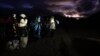 Migrantes solicitantes de asilo se envuelven en mantas para protegerse del viento y la lluvia mientras esperan a ser procesados tras cruzar la frontera con México, en Jacumba Hot Springs, California.