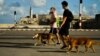 Hombres con mascarillas de protección corren por el Malecón de La Habana. (Yamil LAGE / AFP)