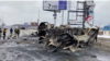 La gente pasa junto a un vehículo destruido en una carretera, en medio de la invasión rusa de Ucrania, en Bucha, Ucrania, el 2 de marzo de 2022 en esta imagen fija tomada de un video.