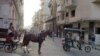 Un carretón con un caballo y un bicitaxi circulan por una calle de La Habana, Cuba.