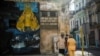 Cubanos en un área restrigida por casos de COVID-19, junto a una imagen de la Virgen de la Caridad. (YAMIL LAGE / AFP)
