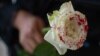 Una mujer sostiene una rosa ensangrentada en protesta contra los feminicidios.